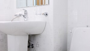 Un baño con lavamanos blanco, espejo e inodoro.