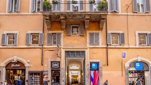 A multi-story building with shops on the ground floor, including a shoe store and a restaurant. - Royal Rooms Corso (Rome)