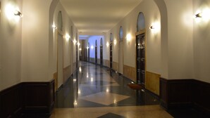 A long, arched hallway with a polished floor and wall sconces. - Royal Rooms Corso (Rome)