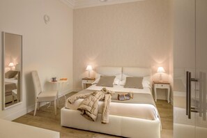 A modern hotel room with a large bed, two bedside tables with lamps, a chair, and a mirror.