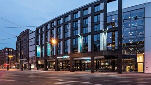 Un hotel moderno con un llamativo letrero de 'Motel One', ventanas amplias y un diseño limpio y contemporáneo.