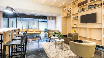 Una sala de estar moderna con un sofá, sillas, una mesa de centro y un televisor en la pared.