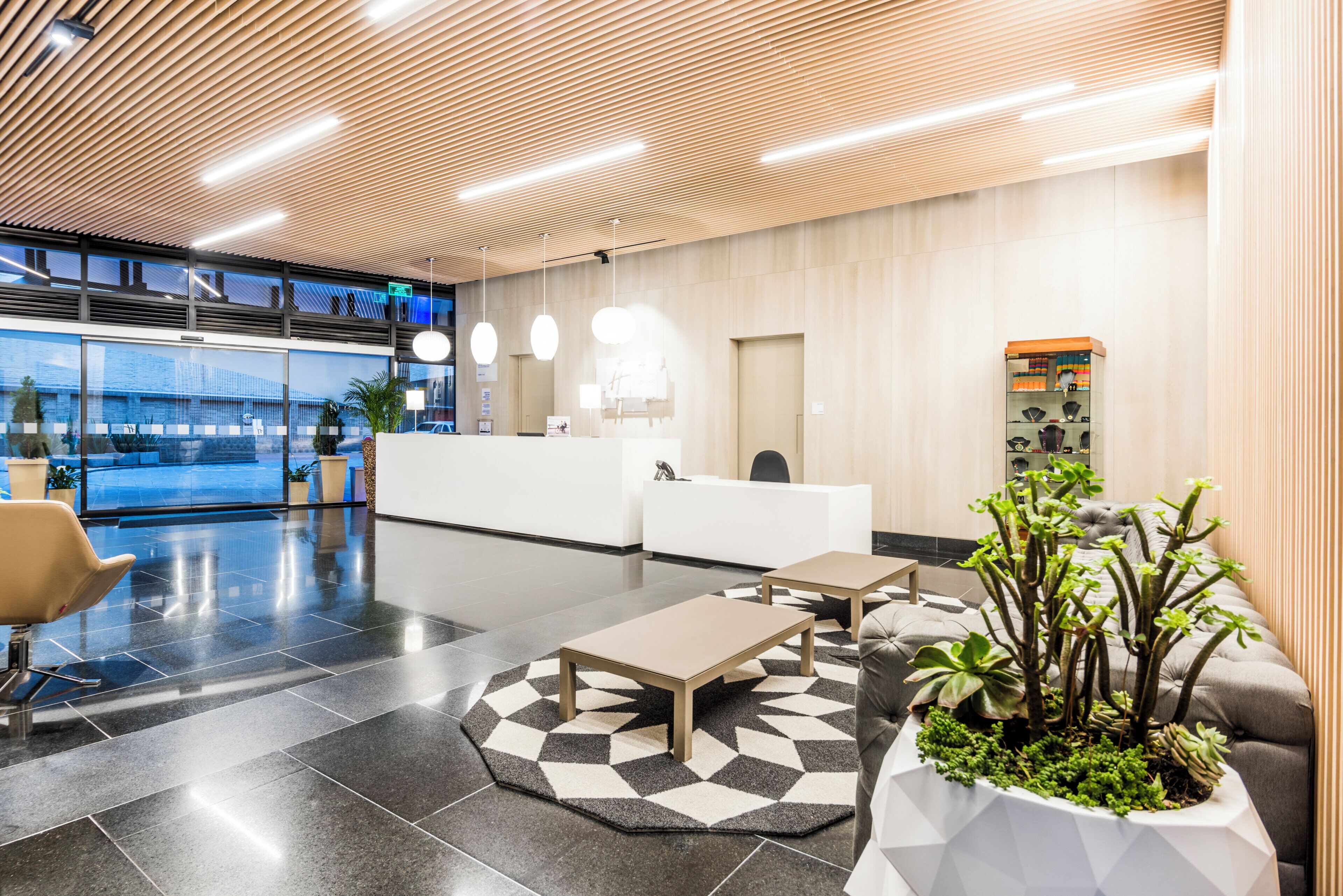 A modern reception area with a reception desk, seating, and a plant.