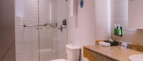A modern bathroom with a glass-enclosed shower, a toilet, and a vanity with a mirror.