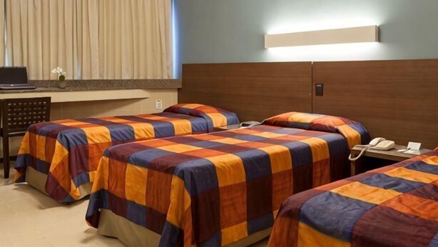 A hotel room with two beds, a desk, and a telephone. - Park Hotel (Recife)