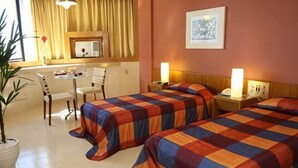 A hotel room with two beds, a desk, a chair, a potted plant, and a painting on the wall. - Park Hotel (Recife)