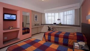 A hotel room with two beds, a TV, a desk with a laptop, a window with curtains, and a mirror. - Park Hotel (Recife)