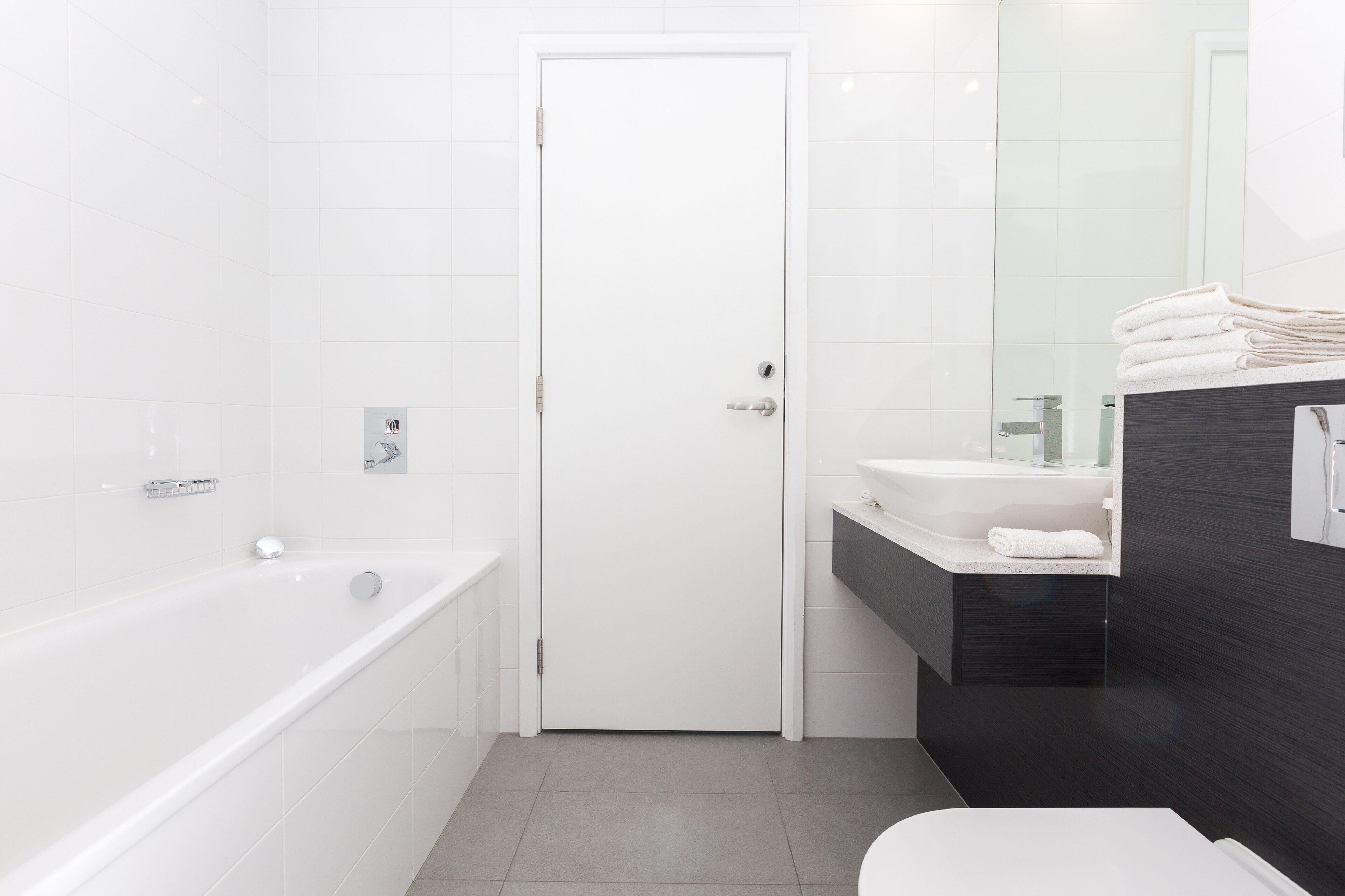 A modern bathroom with a white bathtub, a sink, and a toilet.