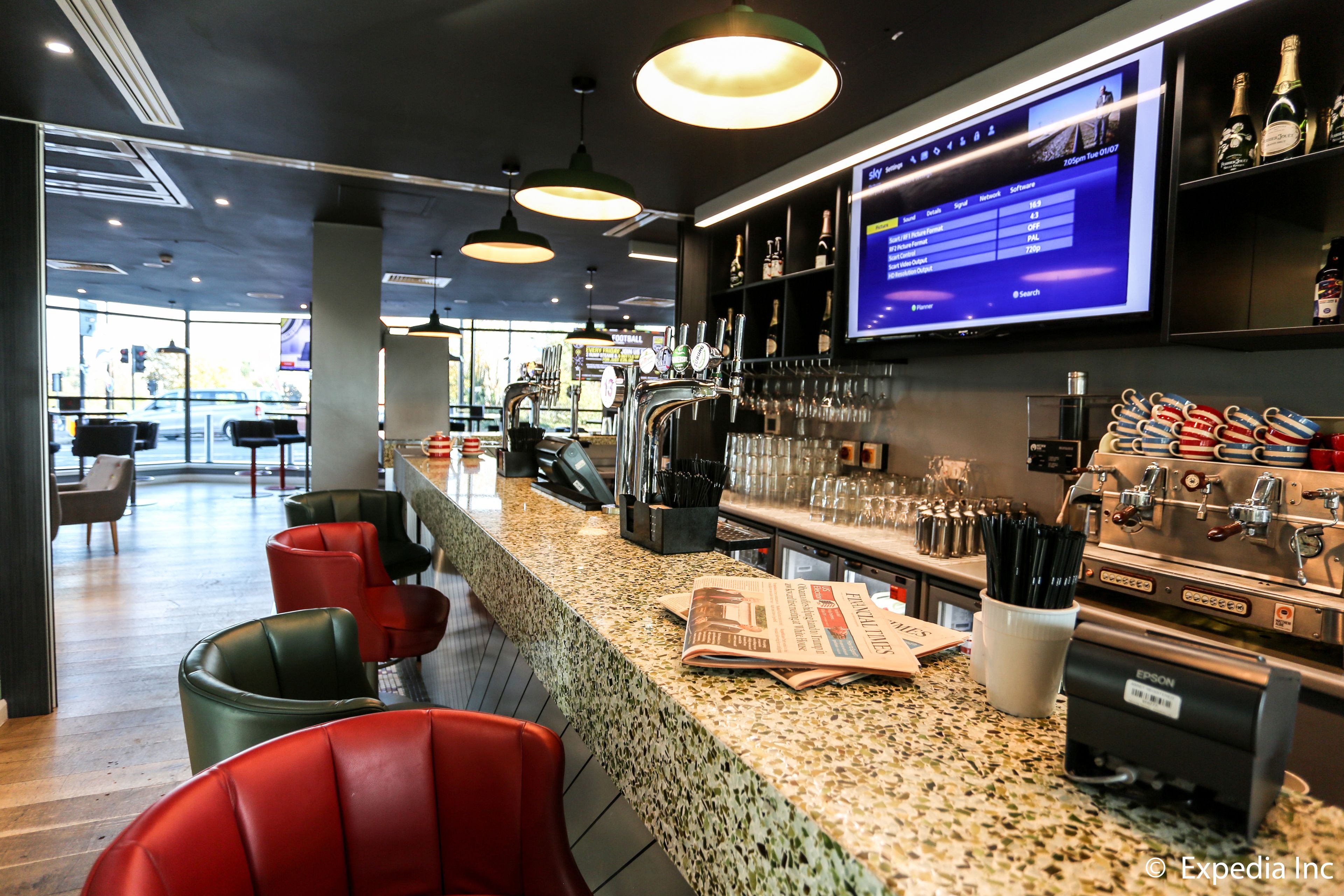 Un espace bar avec des sièges, un écran de télévision et une machine à café.