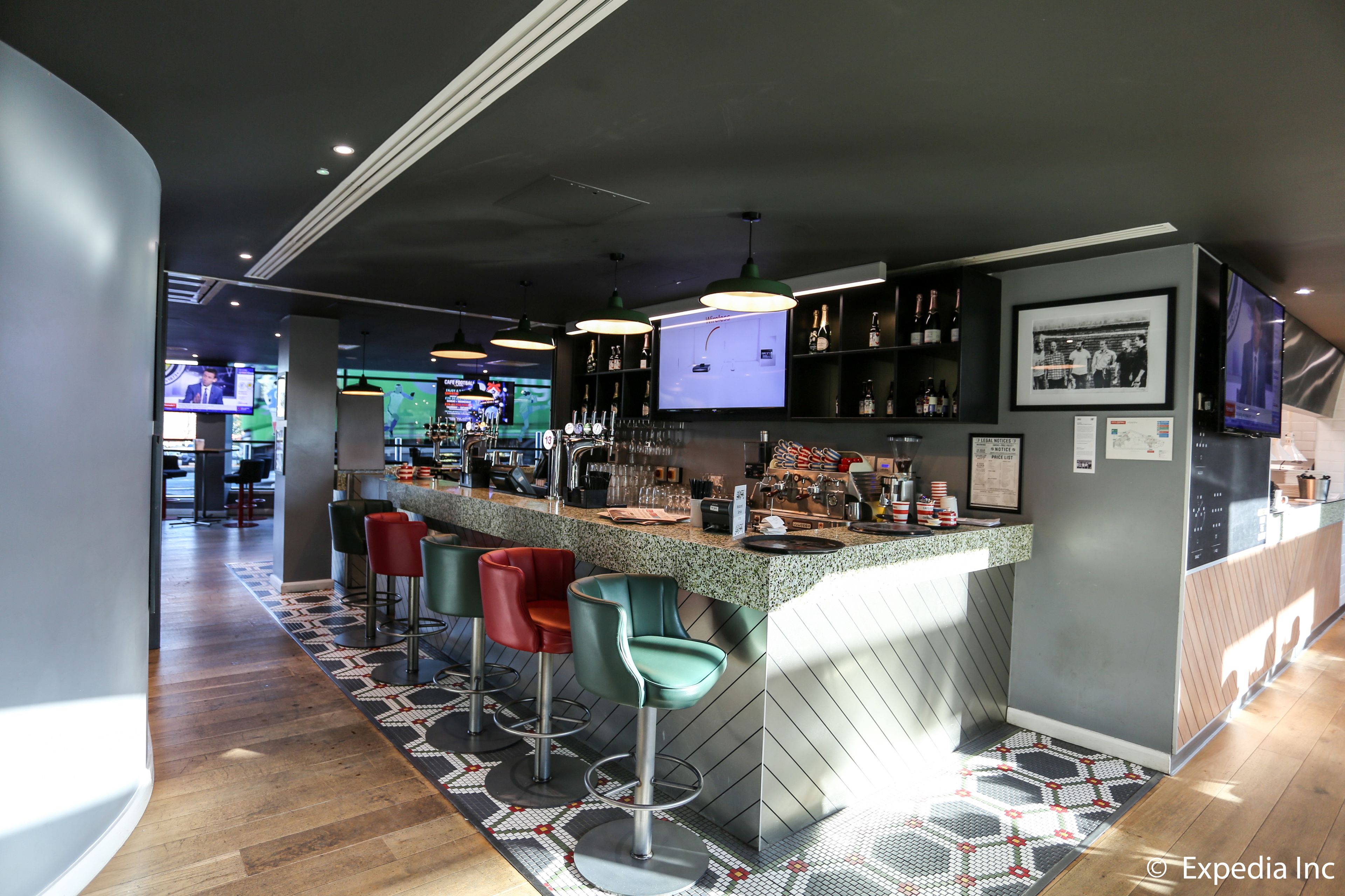A modern bar area with a counter, stools, and a television screen.