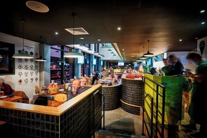 A modern restaurant interior with high ceilings, pendant lighting, and a central counter. - Hotel Football, Old Trafford, a Tribute Portfolio Hotel (Manchester)
