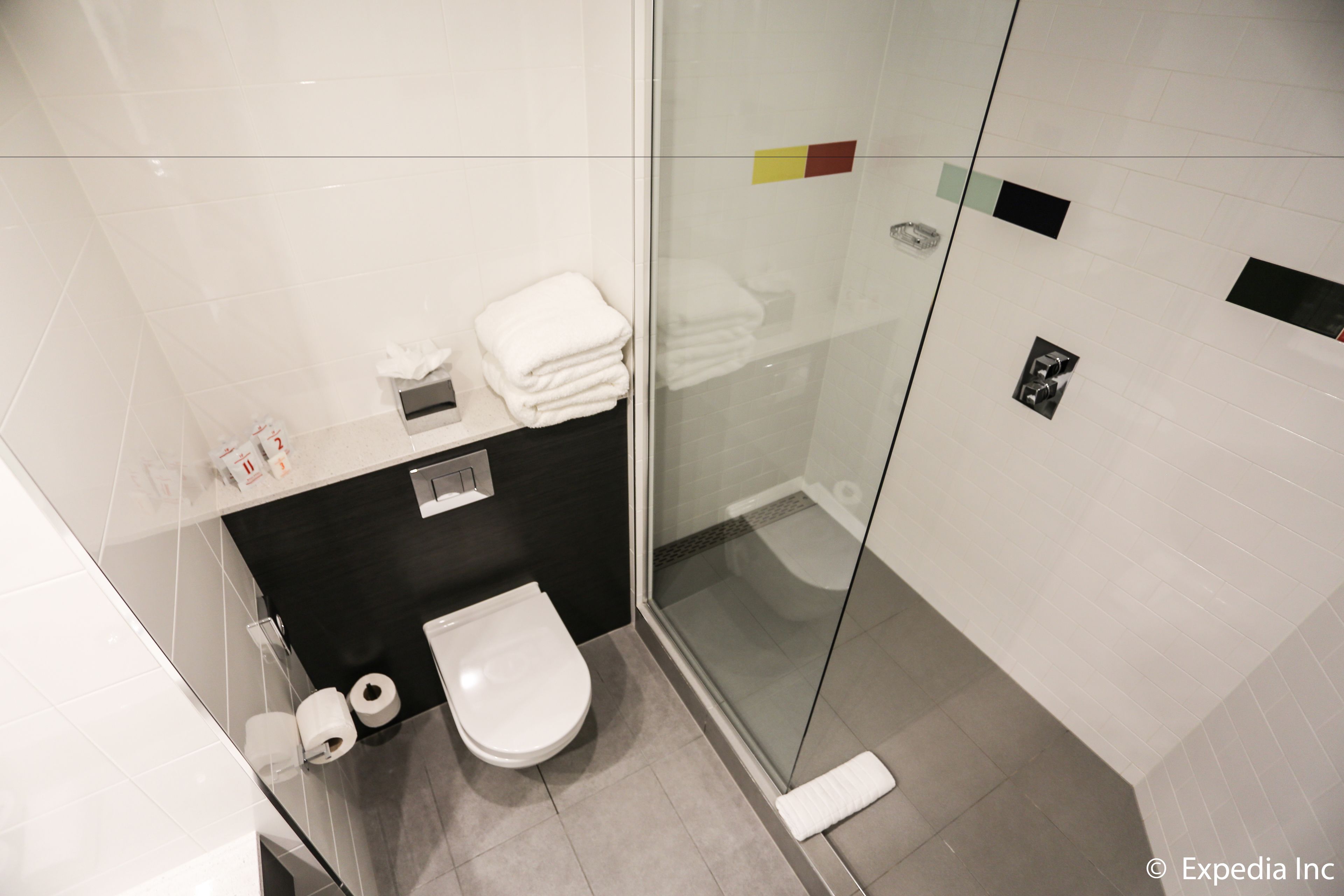 Un baño moderno con inodoro, cabina de ducha de vidrio y perchero para toallas.