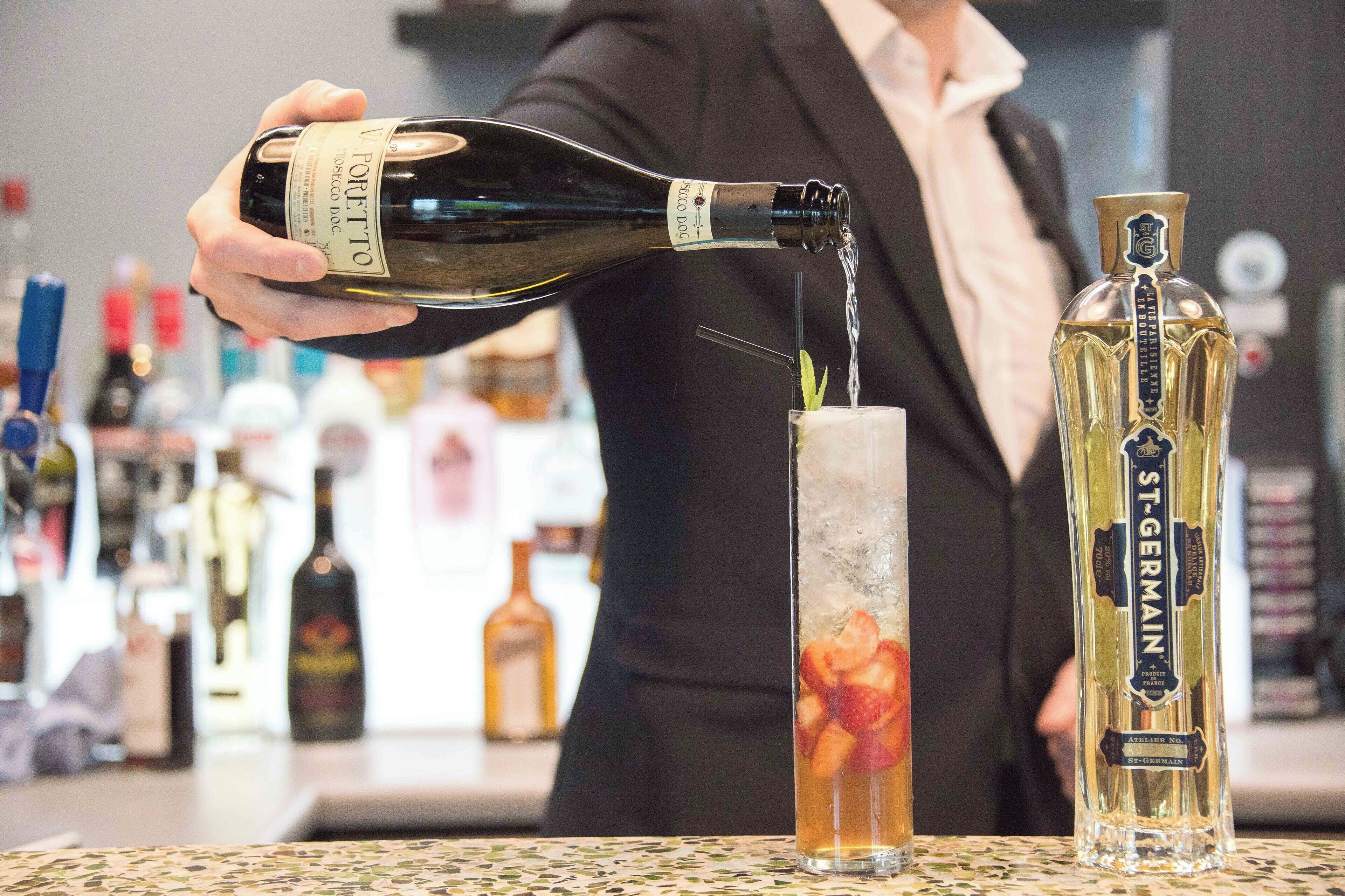 A person pouring a bottle of wine into a glass.