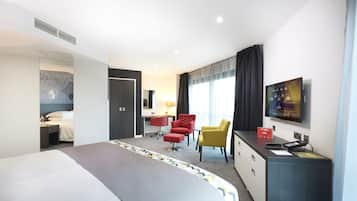 Una camera d'albergo con un letto grande, una scrivania con una sedia, una TV e un minibar.