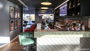 A restaurant interior with a bar area, green chairs, framed pictures on the wall, and a menu sign. - Hotel Football, Old Trafford, a Tribute Portfolio Hotel (Manchester)