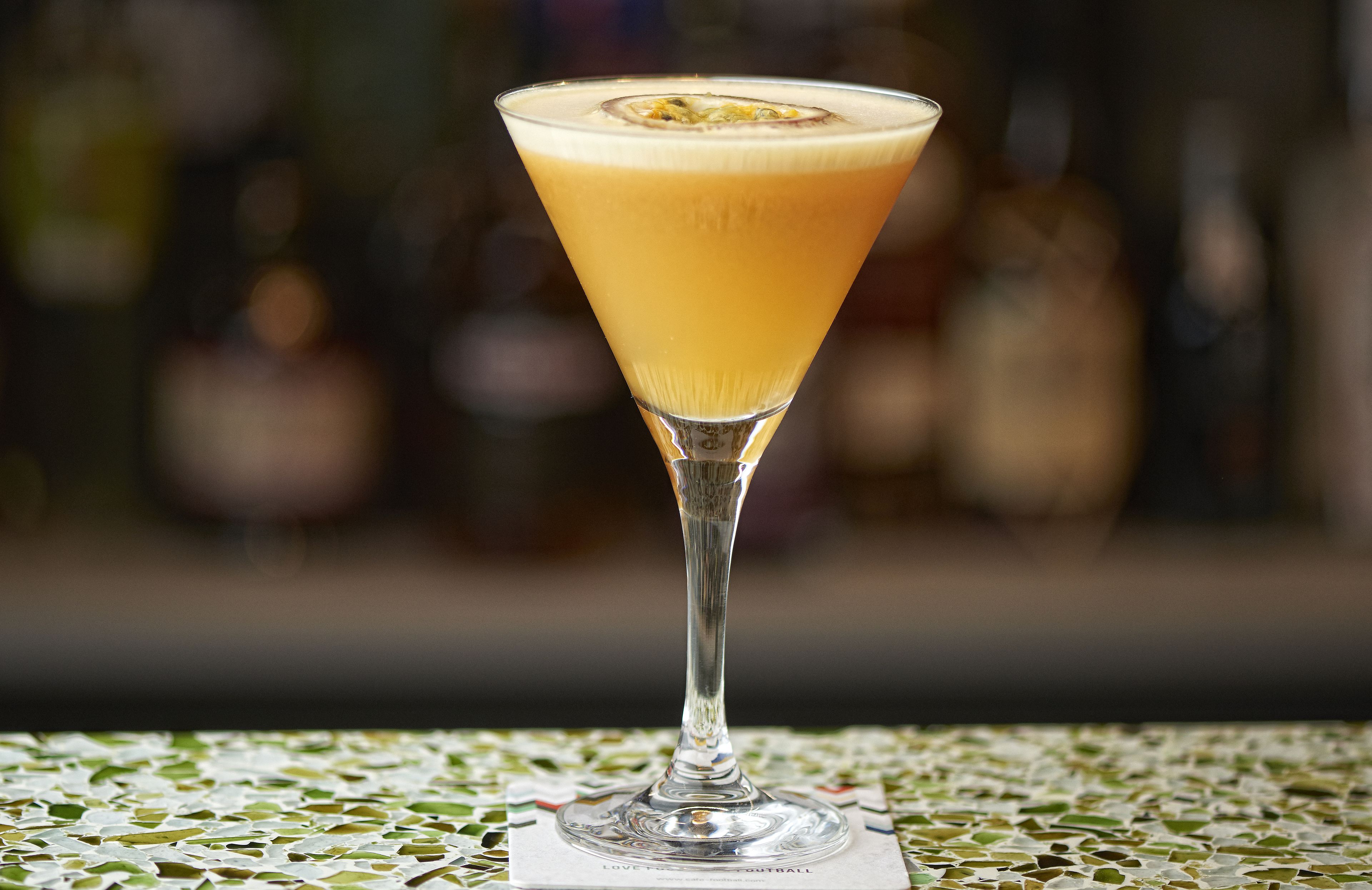 Una copa de martini con espuma sobre una mesa de mosaico.