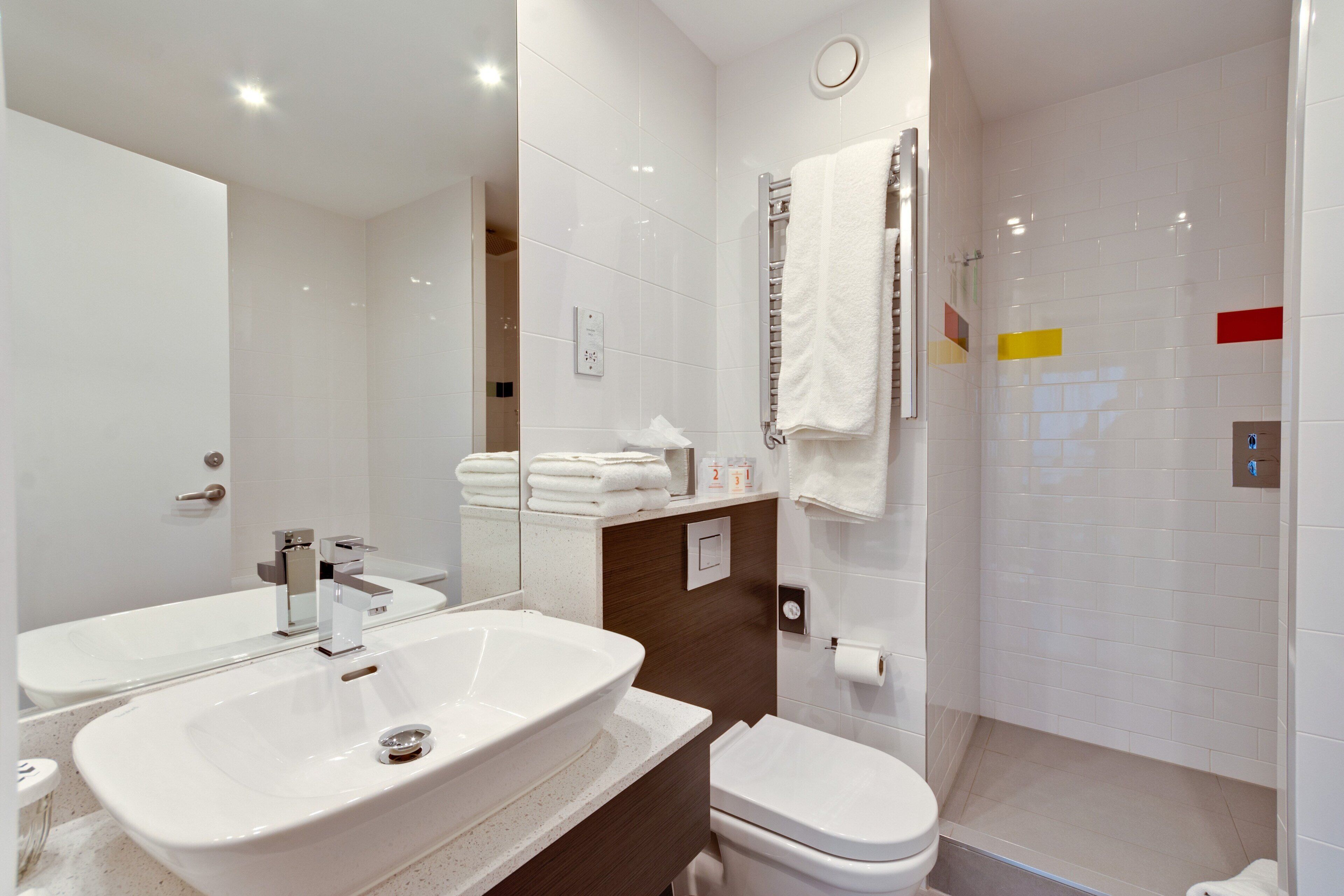 Ein modernes Badezimmer mit zwei Waschbecken, einer Toilette und einer Duschkabine.