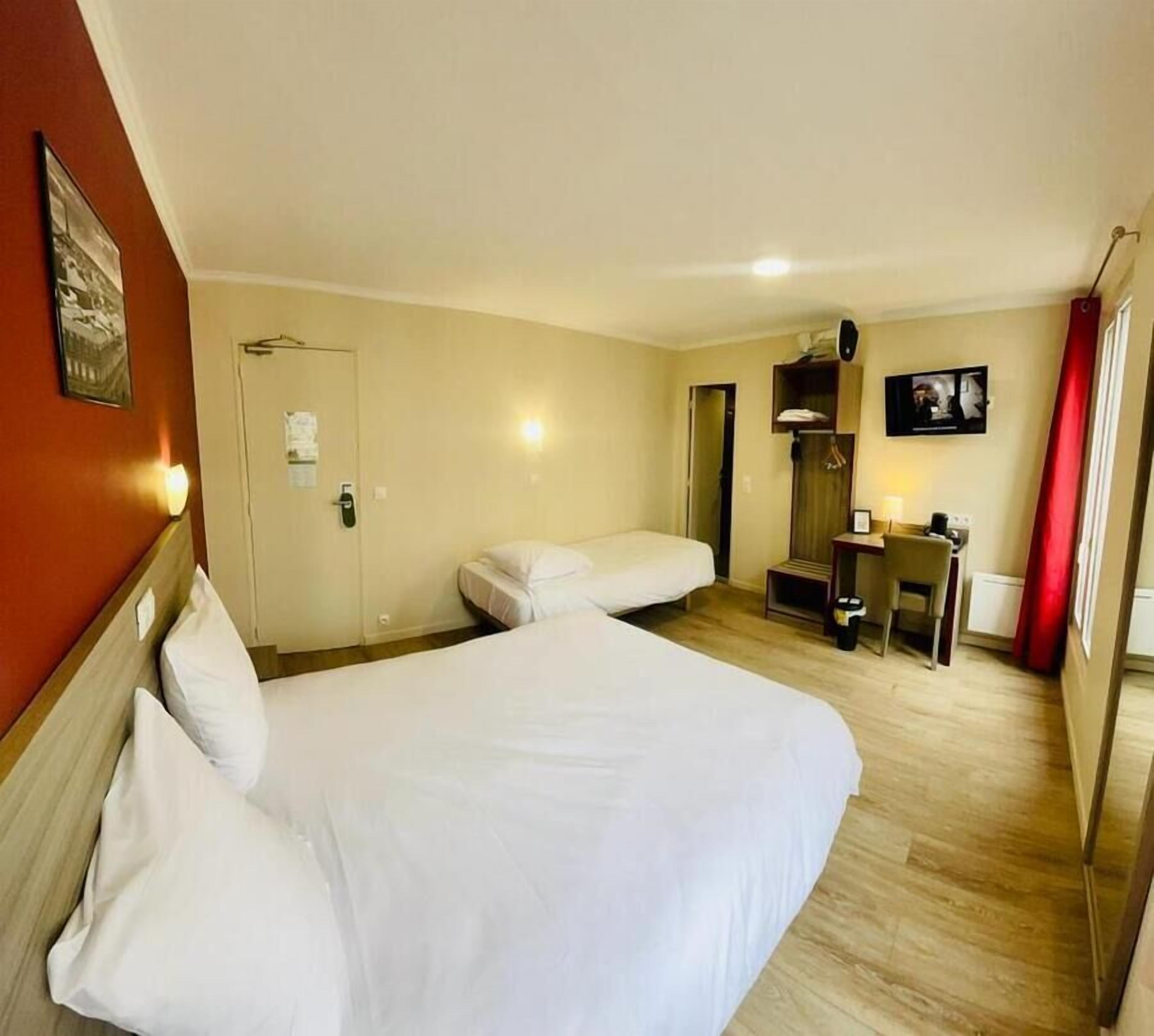 A hotel room with a large bed, a smaller bed, a desk with a chair, a TV, and a red curtain.