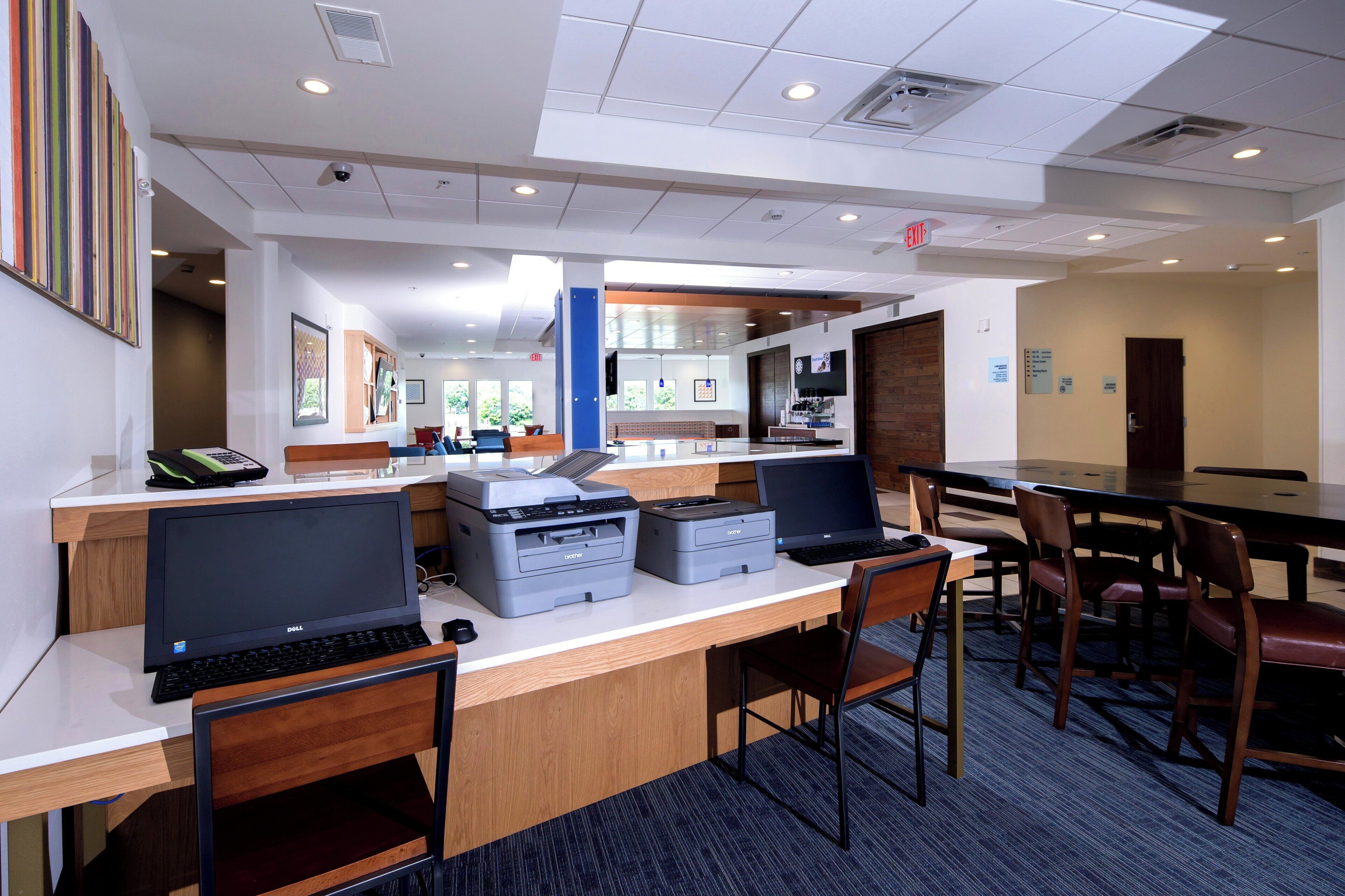 A modern office space with desks, computers, and printers.
