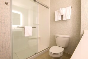 Een moderne badkamer met een douchecabine van glas, een toilet en een handdoekrek met twee handdoeken.