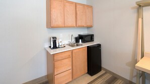 A compact kitchen with wooden cabinets, a black microwave, a coffee maker, and a dishwasher. - Holiday Inn Express & Suites Rochester Hill - Detroit Area by IHG (Rochester)