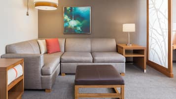 A modern living room with a sectional sofa, a wooden side table, a bench, and a wall-mounted lamp.