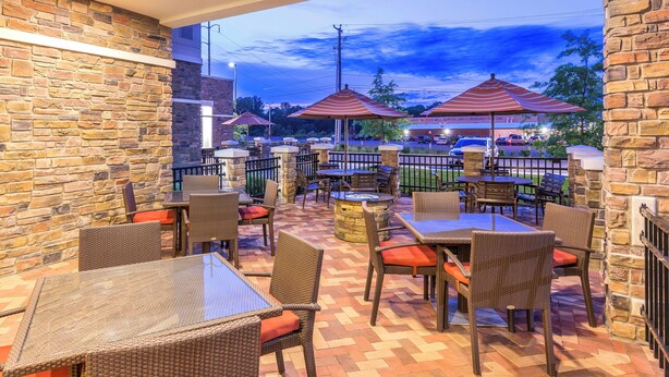 An outdoor patio area with wicker furniture and stone walls. - Hyatt Place Canton (North Canton)