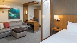 A hotel room with a sofa, a desk, a bed, and a large window. - Hyatt Place Canton (North Canton)