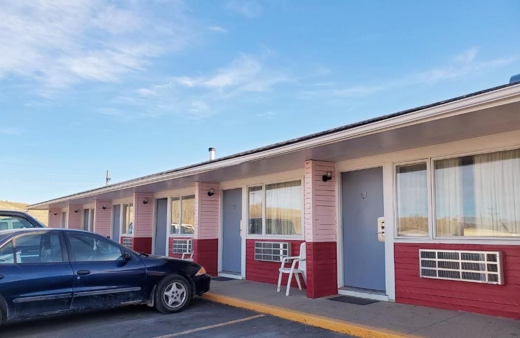 A motel with a row of rooms, each with a window and a door.