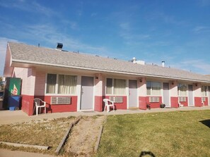 A motel with a row of rooms, each with a window and a door.