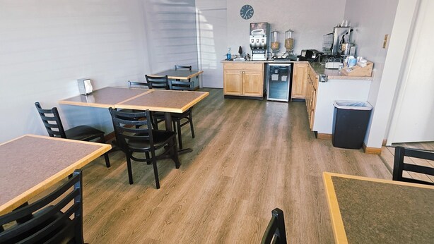 A compact kitchen with a dining area, wooden flooring, and a ceiling fan. - Budget Inn Express (Sheridan)