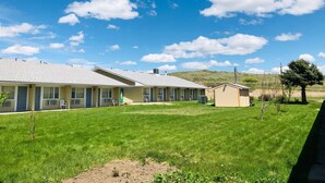 A row of motel buildings with a grassy lawn and a clear blue sky. - Budget Inn Express (Sheridan)