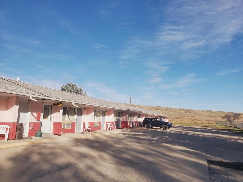 A motel with a single-story structure, a parking area, and a clear sky.