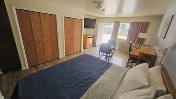 A hotel room with a bed, a desk, a chair, and a view of the outside.