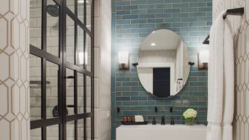 A modern bathroom with a glass shower enclosure, a vanity with a mirror, and a tiled backsplash.