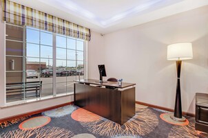 A hotel reception area with a desk, a large window, a lamp, and a carpeted floor.