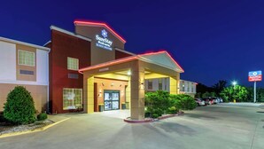 Entrada de hotel con un letrero de SureStay Plus Hotel by Best Western, que presenta un acceso cubierto y un estacionamiento.