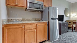 Una cocina moderna con armarios de madera, un refrigerador de acero inoxidable, un microondas y un lavamanos.