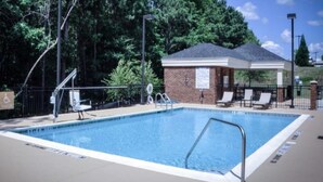 A rectangular pool with a lifeguard chair and a covered seating area with lounge chairs. - Candlewood Suites Columbus-Northeast by IHG (Columbus)