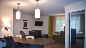 A hotel room with a conference table, two chairs, a sofa, a TV, and a window with curtains. - Candlewood Suites Columbus-Northeast by IHG (Columbus)