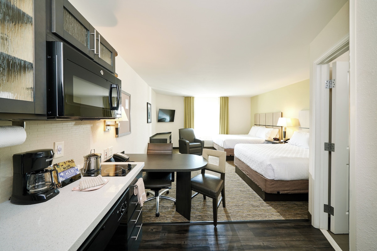 Een hotelkamer met kitchenette, een bed, een bureau en een stoel.