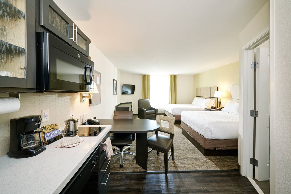 Une chambre d’hôtel équipée d’une kitchenette, d’un lit, d’un bureau et d’une chaise.