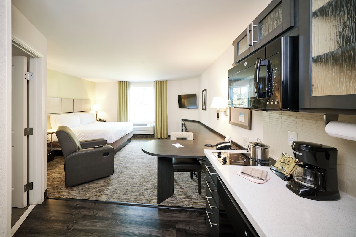 Een hotelkamer met een bed, een bureau, een koffiezetapparaat en een magnetron.