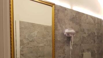 Un bagno con uno specchio grande, un lavandino, un bidet e un asciugacapelli.