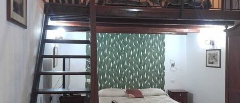 Un dormitorio con una cama litera, una escalera, un escritorio y una silla.