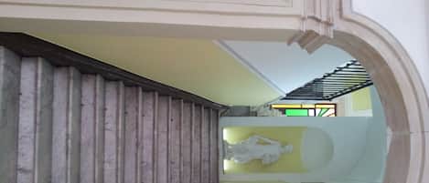 A staircase with a marble-like wall on the left and a yellow wall on the right.