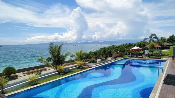 A swimming pool with a view of the sea and mountains. - Hotel On The Rock (Kupang)