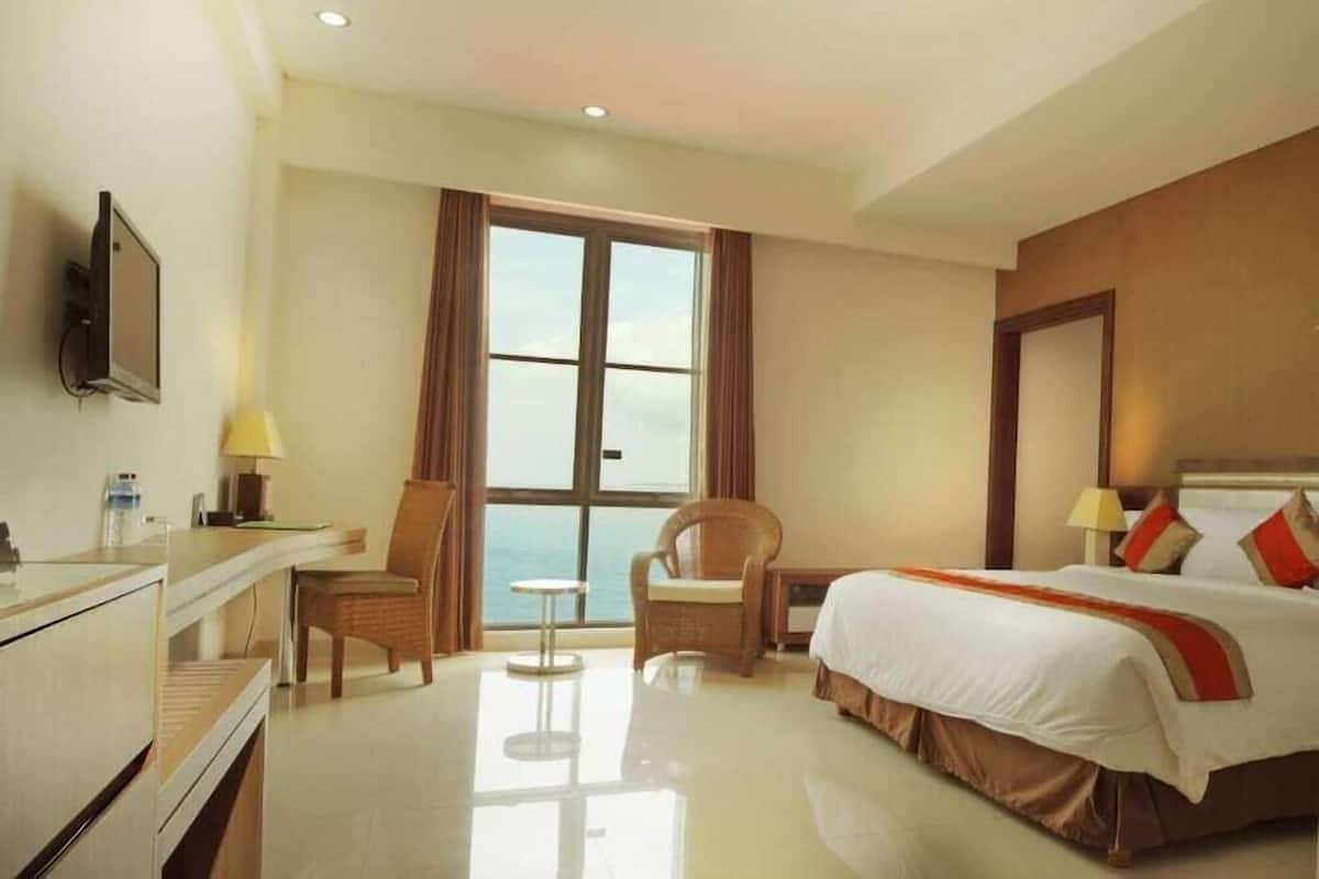 Una habitación de hotel con cama, escritorio, silla, mesita y televisor.