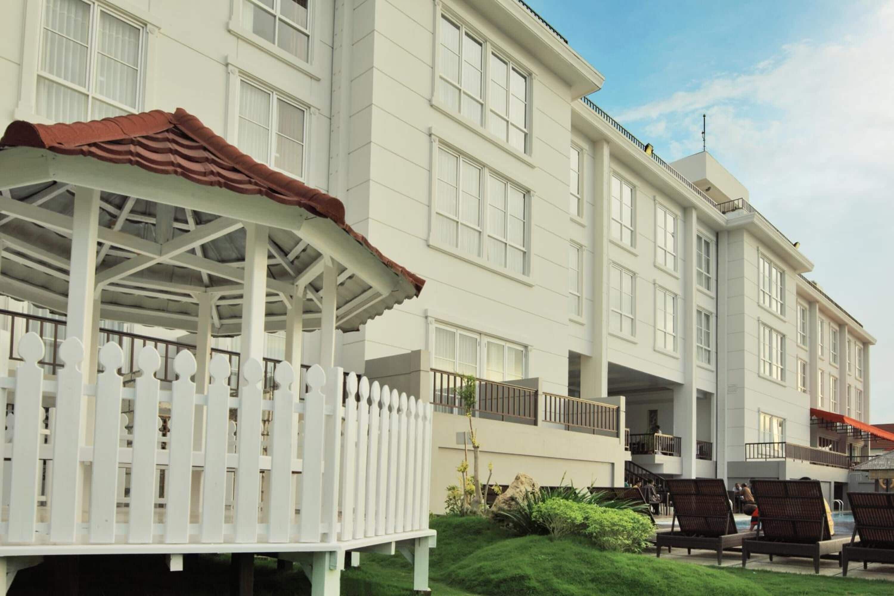 A multi-story hotel with a covered outdoor seating area and a pool.