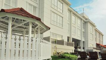 A multi-story hotel with a covered outdoor seating area and a pool.